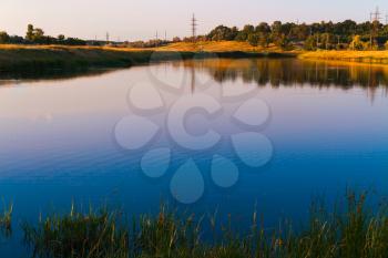 Beautiful colorful summer evening landscape with a reflection of a blue sky in a pond