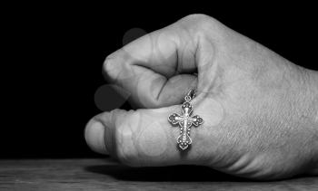 Black and white image of a hand with a cross on a dark background