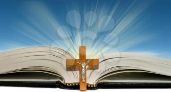 Open book with a wooden cross on a blue background with rays of light
