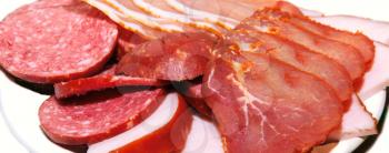 Sliced meat products of several kinds spread out on a plate close up