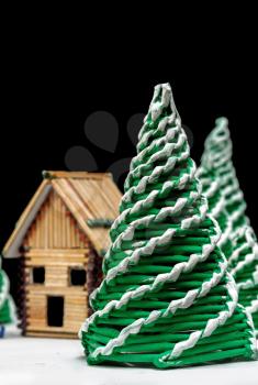 Toy spruces and a house close up on a dark background