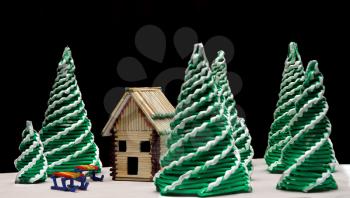 Toy spruces and a house on a dark background