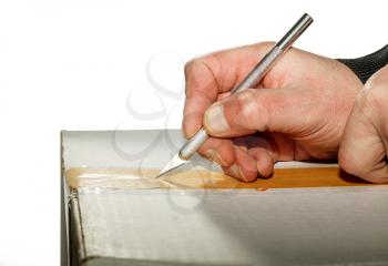 Hands with a knife-scalpel open a carton box isolated on a white background