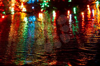 Multi-colored lights on a dark background on a reflective surface