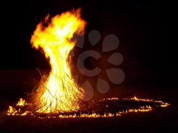 Big bonfire in the night in a circle of burning branches on a dark night