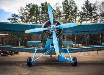 Blue airplane with propeller. Vintage biplane. Front view, with the side of the fuselage. Old retro plane close-up.