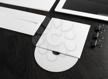 Blank compact disk on wooden table. Fragment of blank stationery and corporate identity template on dark background. Template for branding identity for designers. Shallow depth of field.
