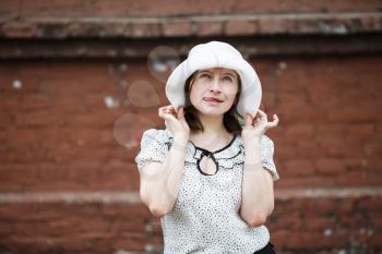 Pretty young woman in white hat posing and showing tongue