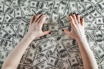 Female hands on a background of money. Hands and money. Many one hundred dollar bills. Fake money. Business concept. Top view.