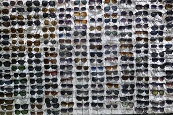Many sunglasses on white wall background. Showcase with glasses.