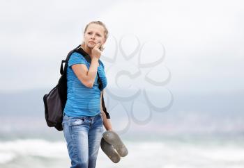Pretty young blonde woman with a backpack standing outdoors. Girl with backpack. Selective focus on model.