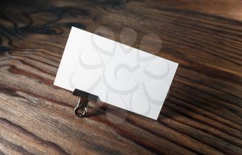 Photo of blank business card with soft shadow on dark brown wooden background. Mock-up for branding identity.