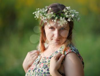Portrait of a pretty young woman with a wreath on his head in the sunset light. Sunset light. Shallow depth of field. Focus on eyes.
