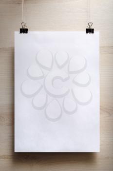 Blank white poster on a light wooden background. Vertical shot.