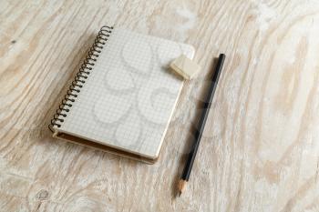 Notebook with a pencil and eraser on light wooden background with soft shadows. Template for graphic designers portfolios. Top view.