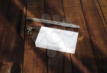 Blank business cards, pen and paper clip on vintage wooden table background.