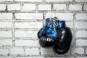 Boxing gloves hanging on a white brick wall.