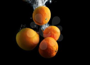 Orange and tangerines in water with air bubbles. Wash fruits. Photo on a black background.