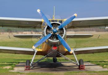 Retro airplane on green grass. Frontal view of the propeller engine and cockpit.