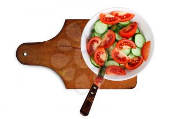 Ripe cucumbers and tomatoes on a white plate on a cutting board.. Clipping path