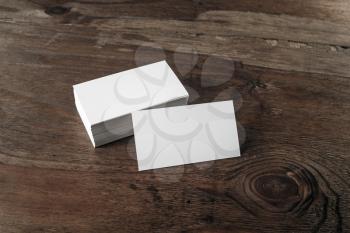 Photo of blank business cards with soft shadows on dark brown wooden background. Blank template for design presentations and portfolios.