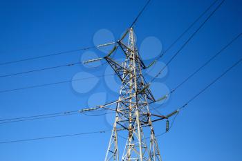 High voltage tower against blue sky background. Electricity pylon.