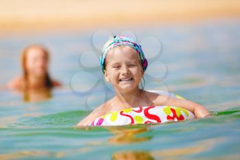 Happy child girl swims in the sea on inflatable ring on a clear sunny day. Shallow depth of field. Selective focus.