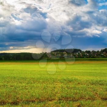 Rural landscape with a field of green grass and dramatic evening sky.