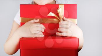 Big red gift box in the children hands. Child holding red gift box with golden ribbon.