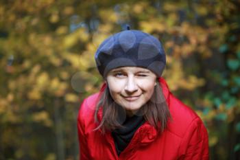 A smiling young woman winks at the camera. Autumn portrait of a woman. Shallow depth of field. Selective focus on the eyes of the model.