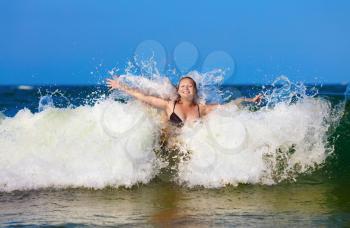 Young woman enjoying a dip in the sea on a background of foam and spray