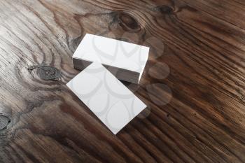 Photo of blank white business cards with soft shadows on dark wooden background. For design presentations and portfolios.