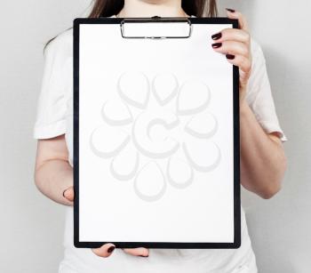 Blank paper in clipboard in female hands. Mock-up for design presentations and portfolios.