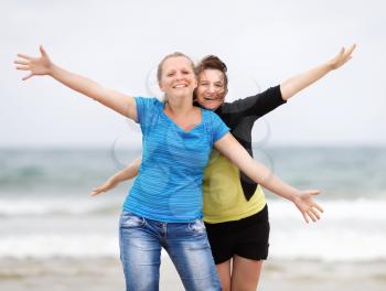 Two happy women on the beach with open arms enjoying their freedom. Shallow depth of field.