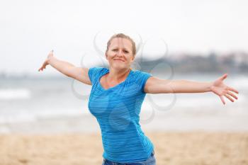 Free happy woman  in a blue t-shirt enjoying at the beach with arms open enjoying her freedom.