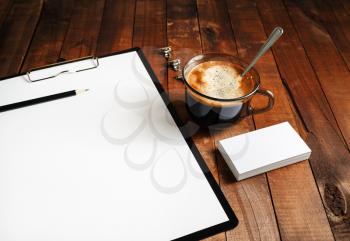 Close-up of blank paperwork template. Blank stationery set on vintage wooden table background. Paper, blank letterhead, coffee cup and pencil. Mock-up for design portfolios. Top view.