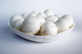 Photo of white eggs on a white square dish on a light background.