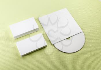 Blank business cards and compact disk on a green background. Template for ID