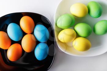 Colorful Easter eggs on a black and white plates. Top view.