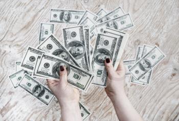 Dollars in hands. Cash in hands. Fake money in hands. Money in female hands on light wooden background.