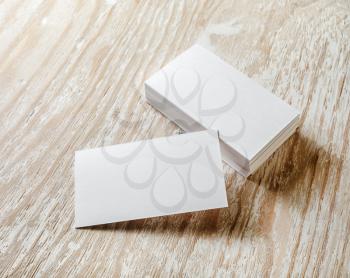 Photo of blank business cards with soft shadows on light wooden background. For design presentations and portfolios.