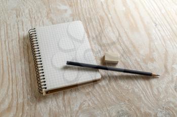 Notepad with a pencil and eraser on a light wooden background