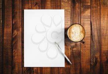 Blank branding template on vintage wooden table background. Letterhead, coffee cup and pen. Blank stationery. Mock-up for branding identity for design portfolios. Top view.