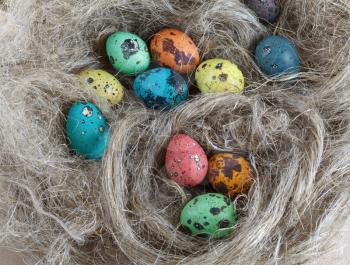 Easter painted quail eggs on a soft linen bedding. Top view.