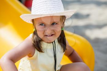 Portrait of a little girl in a white hat and a yellow t-shirt on a clear sunny day. Shallow depth of field. Focus on the model's face.