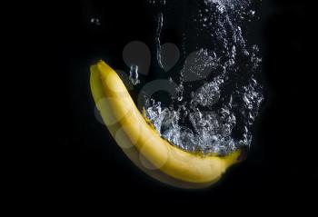 Banana falling into the water with splashes and bubbles. High speed photography.