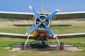 Biplane with blue blue propeller. Old plane close-up. Front view, with the side of the fuselage. Clear sunny day.