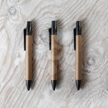 Photo of three blank pens on light wooden background. Mock-up for design presentations and portfolios. Top view.