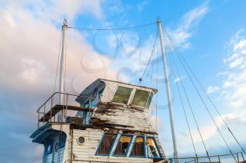 Close-up of a superstructure and the captain's cabin of the old weathered ship on a blue sky background.