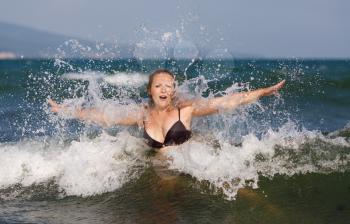 Young woman enjoying a dip in the sea on a background of foam and spray. Shallow depth of field.